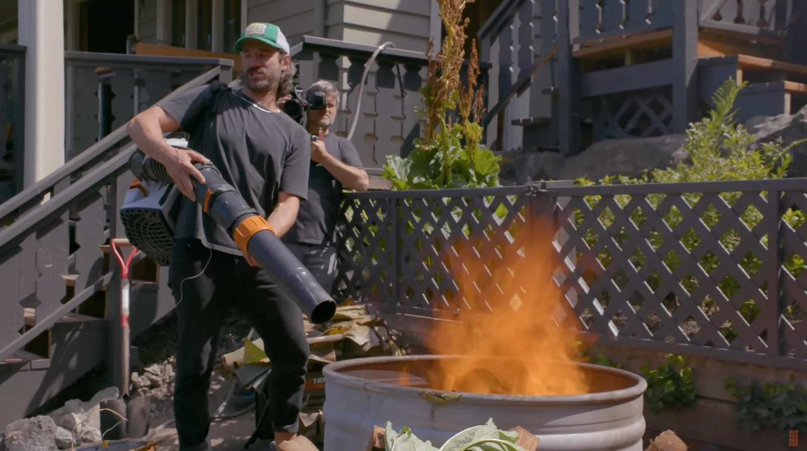 An outdoor ChefSteps cooking scene with a leaf blower feeding a fire in a metal drum