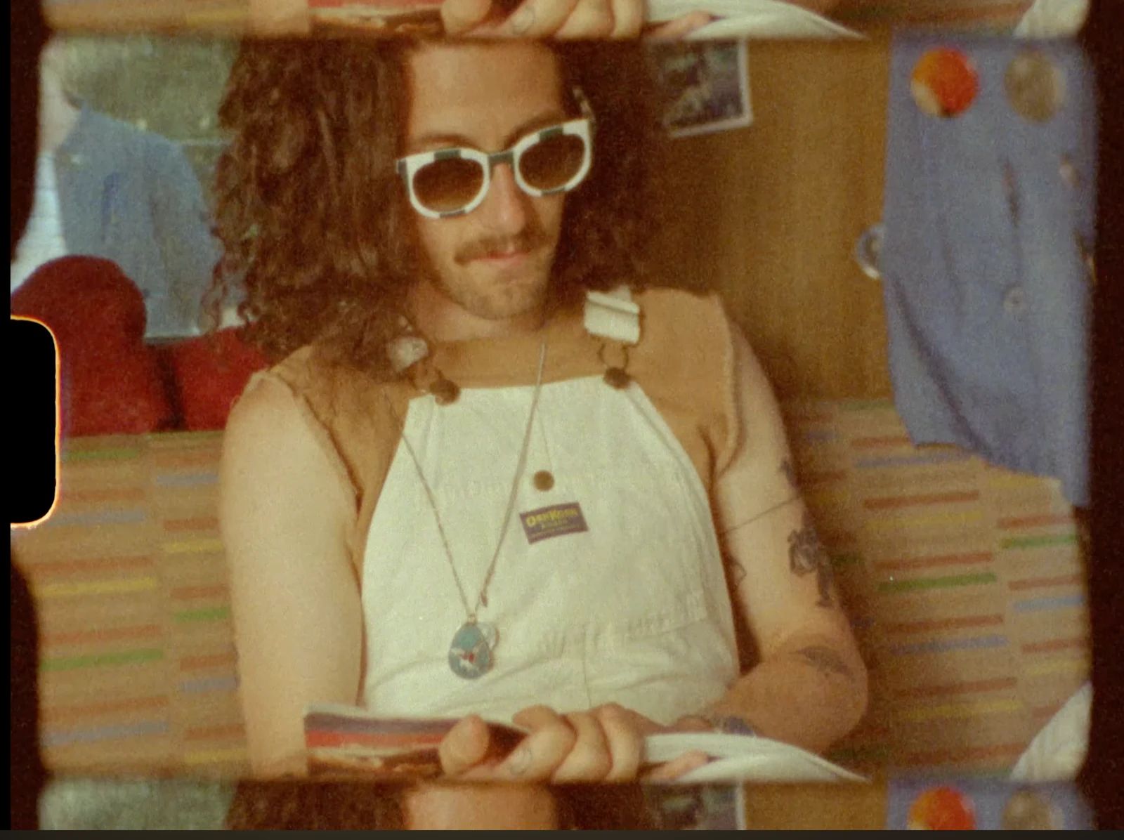 A Super 8 frame of a man wearing white overalls and sunglasses